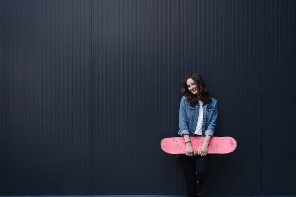 Mooi meisje met krullend haar poseren met een kleurrijke skate — Stockfoto