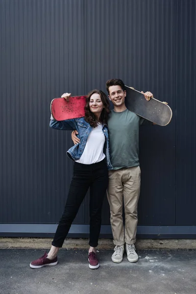 Modernt leende par som står tillsammans med skateboards — Stockfoto