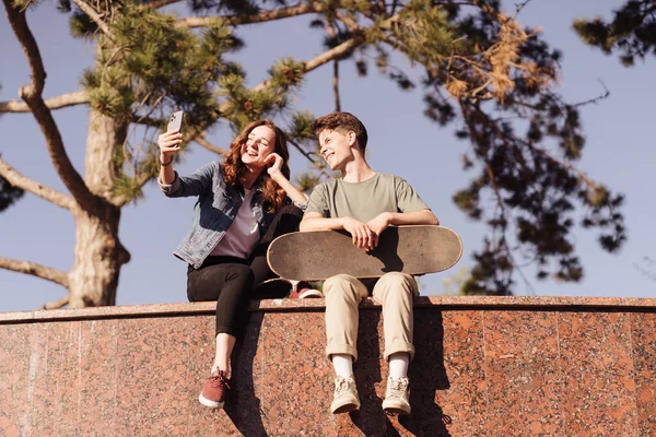 Moderna coppia sorridente in piedi insieme con skateboard — Foto Stock