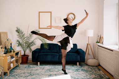 Evde dans eden kadın fotoğraf çekiyor.