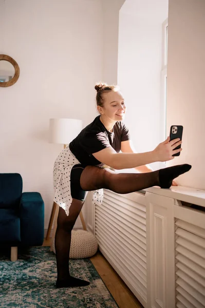 WOMAN SMS på telefon medan sträcker benet på fönstret — Stockfoto