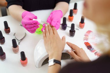 Güzellik salonunda manikürcü müşteriyi tedavi ediyor. Manikür, çivi boyası.