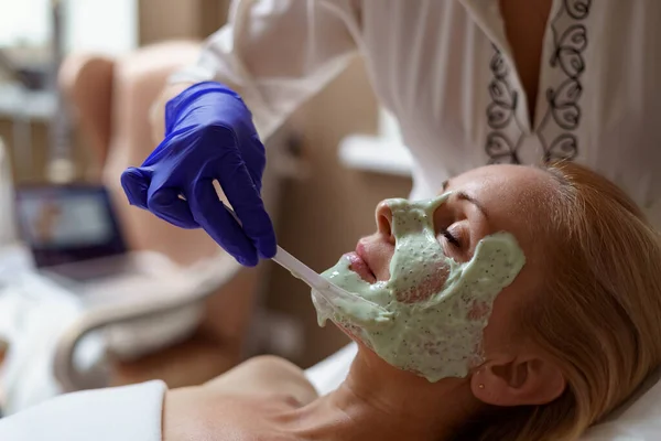 Cosmetician experiente está aplicando máscara saudável na pele feminina — Fotografia de Stock