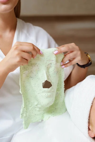 Ervaren schoonheidsspecialiste houdt alginaat masker in haar handen na de procedure — Stockfoto