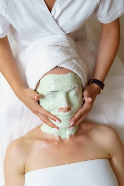 Cosmetician experiente que remove a máscara de alginato de uma cara de uma mulher caucasiana. — Fotografia de Stock