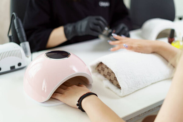 Manicurist treating client at beauty nails salon. Manicure, painting on nail