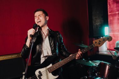 Genç erkek hipster elektro gitar çalıp şarkı söylerken stüdyoda yeni sesler kaydediyor.