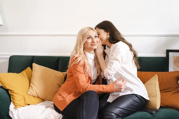 Uma filha adulta está sussurrando algo para sua mãe — Fotografia de Stock