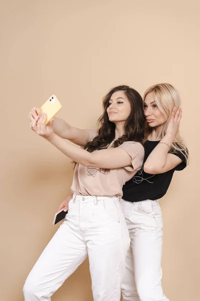 Mãe e filha fazendo selfie no fundo bege — Fotografia de Stock