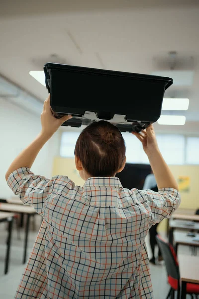 Pojken går medan han håller i en låda med robotkulor som kommer in i hans klass. — Stockfoto