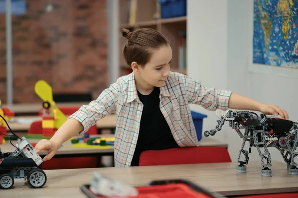 Chytrý školák sedí u stolu a staví robotické zařízení — Stock fotografie