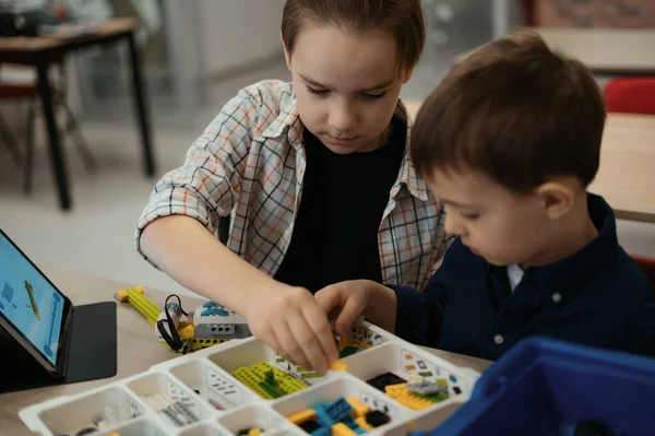 Dva kluci různých věkových kategorií si hrají s robotickou hračkou na škole robotiky — Stock fotografie