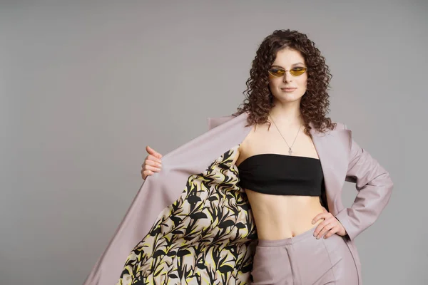 Mujer en cuero ropa elegante y gafas de sol verdes sobre fondo gris estudio —  Fotos de Stock