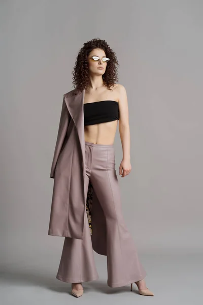 Mujer en cuero ropa elegante y gafas de sol verdes sobre fondo gris estudio —  Fotos de Stock