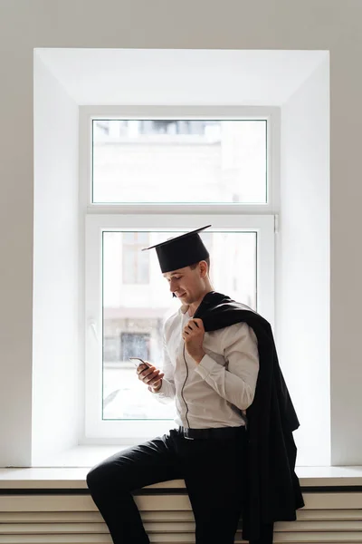Caucasian young man feeling very excited to receive his bachelors degree using phone — Stock Photo, Image