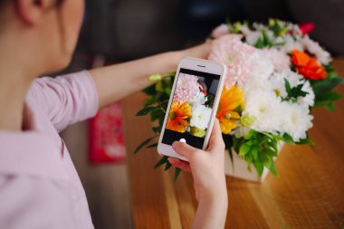 Akıllı telefondan çiçek kompozisyonu alan kadın