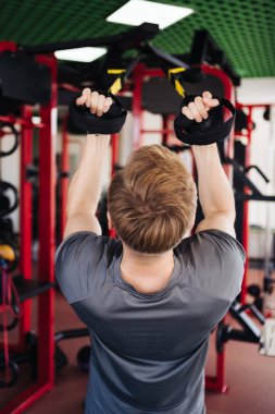 Genç sporcu spor salonunda direniş sistemiyle antrenman yapıyor.