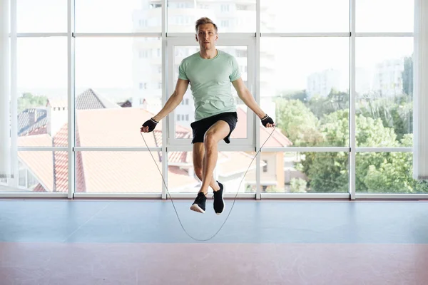 Przystojny młodzieniec skaczący przez skakankę ćwiczący — Zdjęcie stockowe