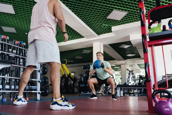 Jovem tem treino com personal trainer no ginásio — Fotografia de Stock