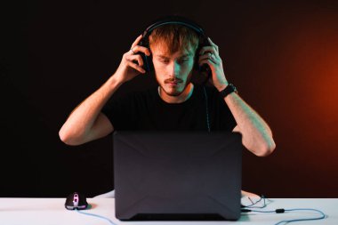Neon ışıklı arka planda kulaklıkla video oyunu oynayan oyuncu