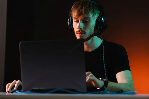 Neon ışıklı arka planda kulaklıkla video oyunu oynayan oyuncu