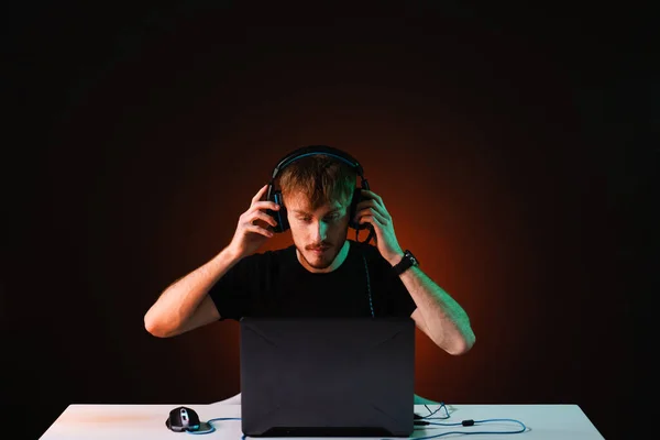 Neon ışıklı arka planda kulaklıkla video oyunu oynayan oyuncu — Stok fotoğraf