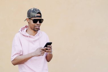 Sarı arka planda telefon kullanan güneş gözlüklü adam.