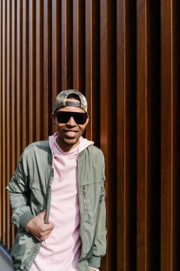 Ahşap arka planda poz veren kendinden emin genç Afro adamın portresi.