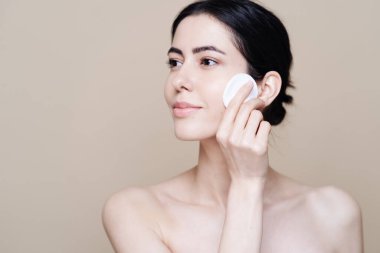 Genç esmer kadın makyajını temizliyor.