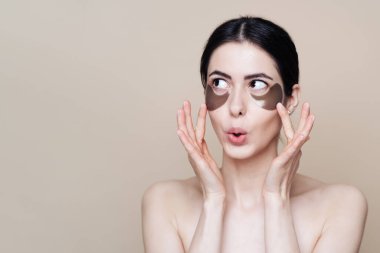 Temiz yüz derisi olan genç ve güzel bir kadın, göz bandı kullanıyor.