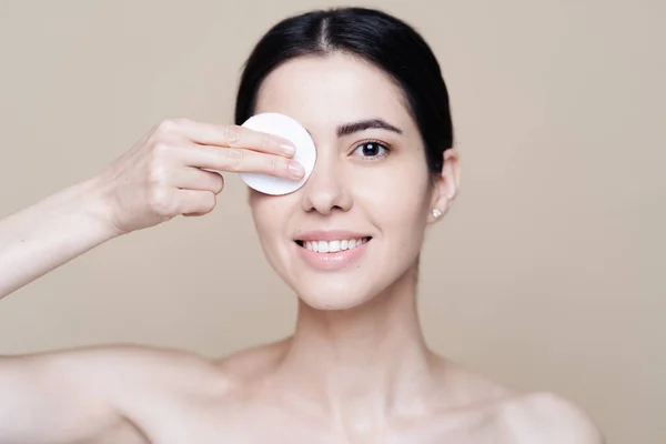 Young brunette woman removing makeup from her face — Stock Photo, Image