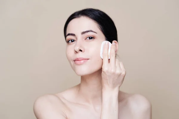 Young brunette woman removing makeup from her face — Stock Photo, Image