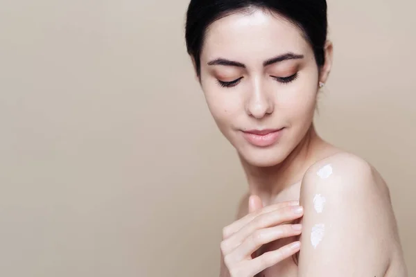 Beautiful Caucasian woman applying cream on face — Stock Photo, Image