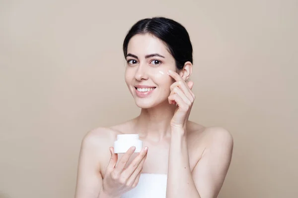 Mooie blanke vrouw aanbrengen crème op gezicht — Stockfoto