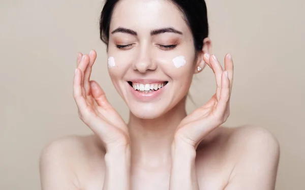 Mooie blanke vrouw aanbrengen crème op gezicht — Stockfoto