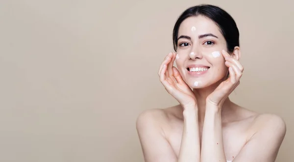 Beautiful Caucasian woman applying cream on face — Stock Photo, Image