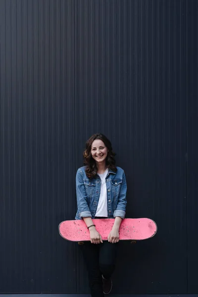 Mooi meisje met krullend haar poseren met een kleurrijke skate — Stockfoto