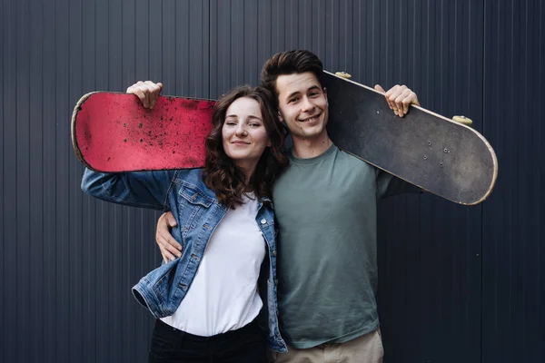 Moderna coppia sorridente in piedi insieme con skateboard — Foto Stock