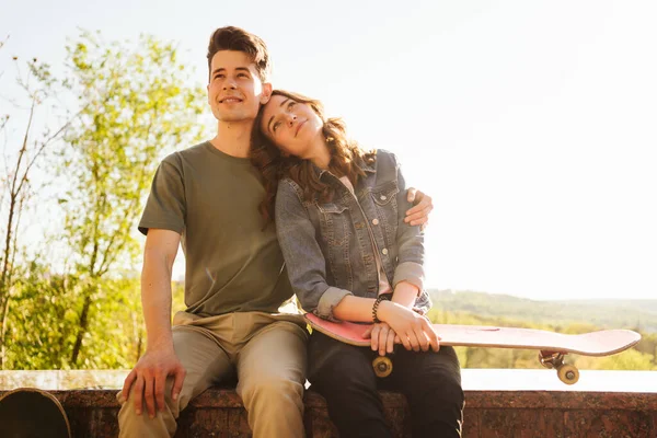 Pareja sonriente moderna de pie junto con patinetas —  Fotos de Stock