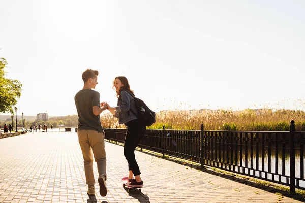 Guy gibt seiner Freundin eine Lektion in Skateboarden. — Stockfoto