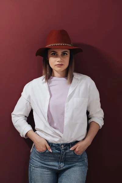 Retrato de uma mulher bonita usando chapéu sobre fundo borgonha — Fotografia de Stock