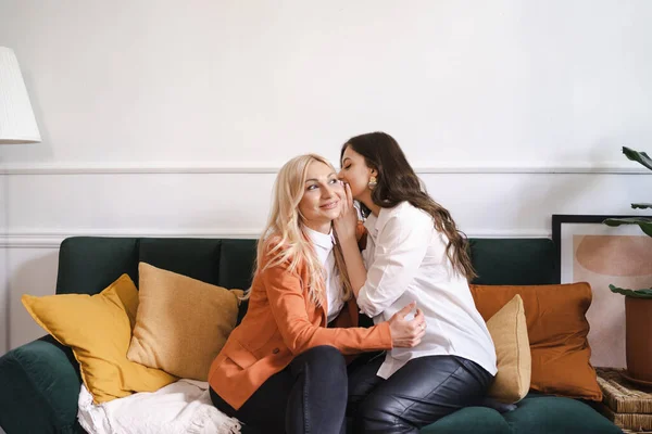 Uma filha adulta está sussurrando algo para sua mãe — Fotografia de Stock