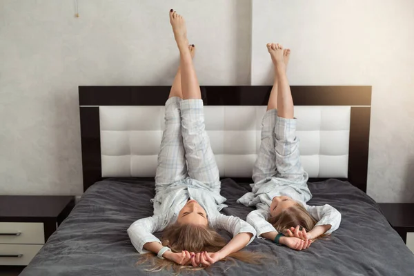 beautiful mom with daughter in pajamas at home on the bed upside down