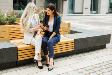 Cep telefonlu takım elbiseli iki güzel genç bayan.