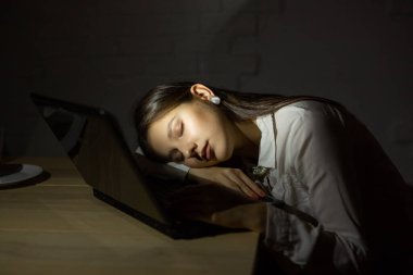 Güzel genç bayan geceleri bir dizüstü bilgisayarın arkasında uyuyor.