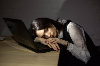 Güzel genç bayan geceleri bir dizüstü bilgisayarın arkasında uyuyor.