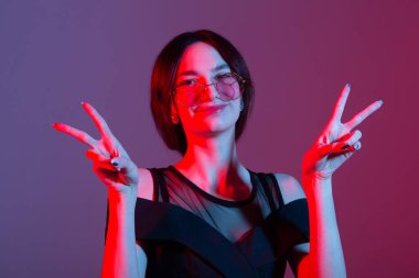 Güneş gözlüklü, renkli ışıklandırmalı güzel bir genç kadının portresi.