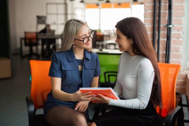 iki güzel genç bayan ofiste koltuklarda. 