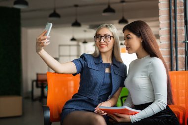 Ofisteki iki güzel genç bayanın telefonda fotoğrafları çekiliyor. 