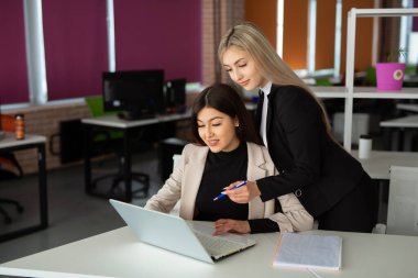 Ofiste dizüstü bilgisayarı olan iki güzel genç kadın. 